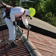 Pracownik w kombinezonie ochronnym usuwa eternit z dachu. To pierwszy krok do wymiany dachu z eternitu krok po kroku, dotacje i utylizacja azbestu.