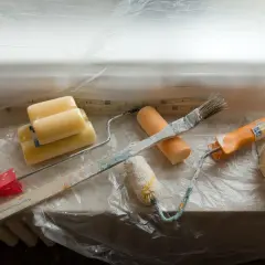 Narzędzia malarskie i taśma malarska przy oknie. Ostrożnie odrywaj taśmę, by nie uszkodzić uszczelki.