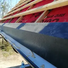 Błędy w obróbce pasa nadrynnowego powodują, że woda leci po ścianie. Widoczna konstrukcja dachu z membraną i rynna.