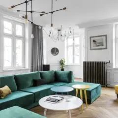 Elegancki salon z butelkową zielenią kanapy, żółtym fotelem i stolikami. Z czym połączyć butelkową zieleń? Zobacz inspiracje.