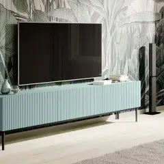 Elegancka szafka RTV z telewizorem na ścianie, idealna do wnętrz z motywem roślinnym. Dowiedz się, jak ukryć kable od telewizora na ścianie bez kucia.