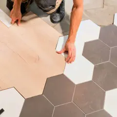Ręczne łączenie paneli podłogowych z płytkami ceramicznymi w kształcie heksagonów, tworząc płynne przejście bez widocznej listwy progowej.
