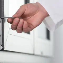 Dłoń reguluje okucie okna, gdy uchyla się i otwiera jednocześnie. Rozwiązanie problemu błędu okucia.