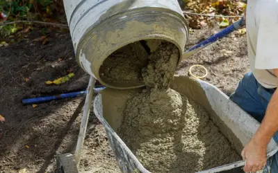 Betoniarka wylewa świeży beton do taczki. Obliczenia i proporcje: ile betonu B20 uzyskamy z worka 25kg suchej mieszanki.