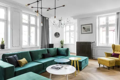 Elegancki salon z butelkową zielenią kanapy, żółtym fotelem i stolikami. Z czym połączyć butelkową zieleń? Zobacz inspiracje.