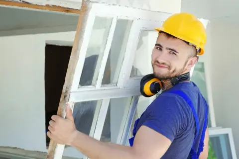Budowlaniec zdejmuje stare okno. Przy dotacji "Czyste Powietrze" zwróć uwagę na współczynnik uw okien.