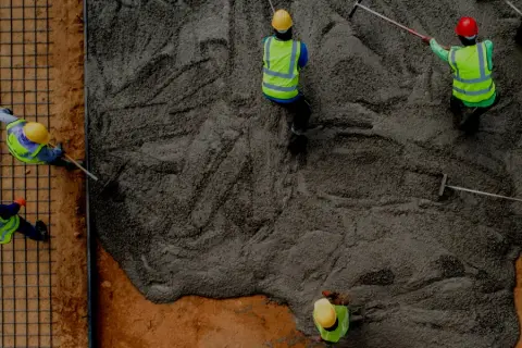 Pracownicy wylewają beton na strop monolityczny. Kluczowe są wymagania konstrukcyjne dla betonu B20 lub B25.