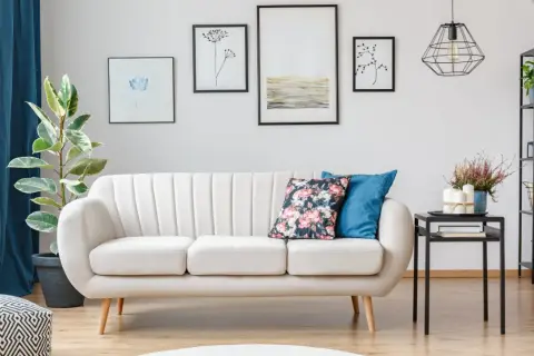 Jasna sofa na nóżkach ułatwia sprzątanie robotem, bo wjedzie pod nią. Wady i zalety tej konfiguracji widać na drewnianej podłodze.