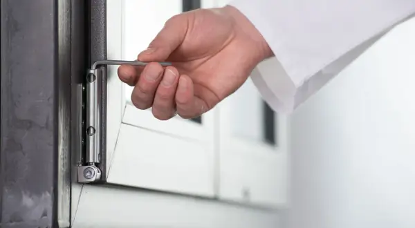 Dłoń reguluje okucie okna, gdy uchyla się i otwiera jednocześnie. Rozwiązanie problemu błędu okucia.