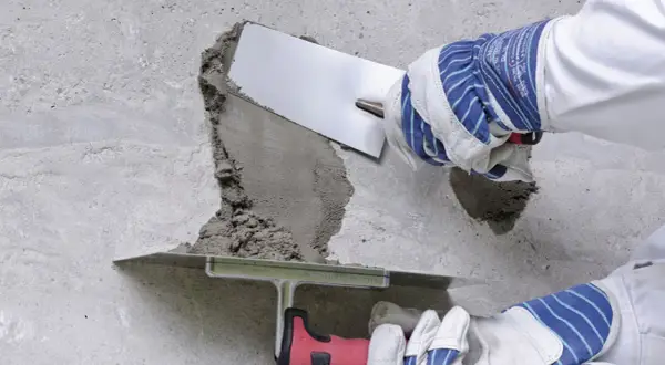 Naprawa betonu: wibrowanie betonu z gruszki zapobiega powstawaniu raków. Użycie kielni do wygładzenia zaprawy.