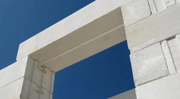Nadproża prefabrykowane czy wylewane na budowie? Analiza kosztów i czasu dla białych bloków na tle błękitnego nieba.