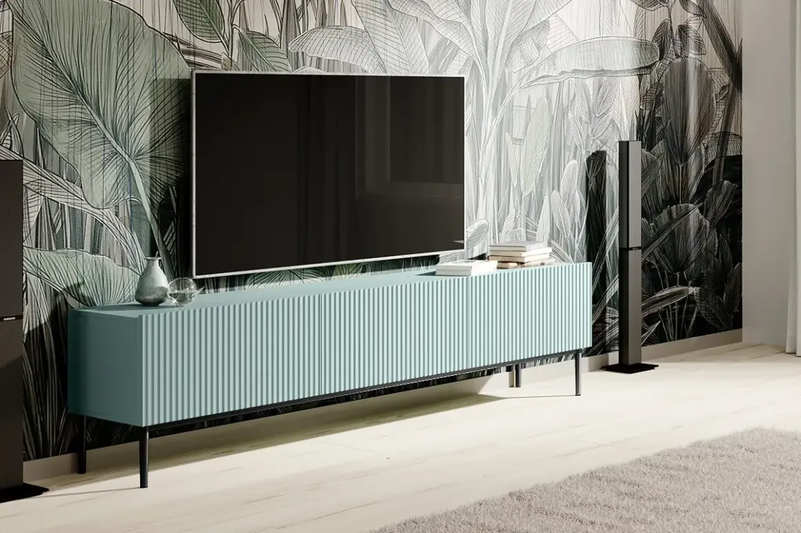 Elegancka szafka RTV z telewizorem na ścianie, idealna do wnętrz z motywem roślinnym. Dowiedz się, jak ukryć kable od telewizora na ścianie bez kucia.