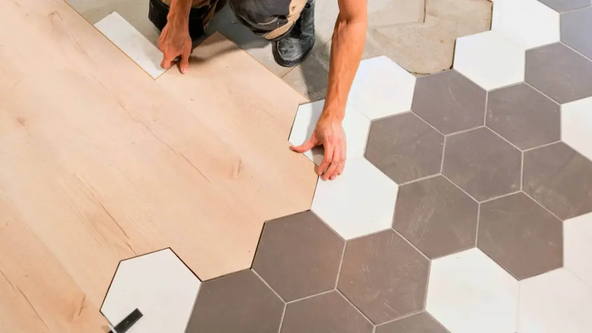 Ręczne łączenie paneli podłogowych z płytkami ceramicznymi w kształcie heksagonów, tworząc płynne przejście bez widocznej listwy progowej.