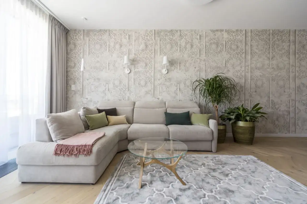 Nowoczesna tapeta panoramiczna w salonie, z subtelnym wzorem, idealnie podkreśla elegancję szarej sofy i drewnianej podłogi.